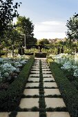 Geometric garden with clipped box hedges, white-flowering agapanthus and planted urn in circular bed