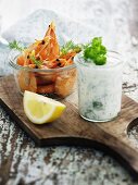 Prawns and herb yoghurt in glasses on a chopping board