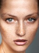 A close-up portrait of a young woman with lots of freckles