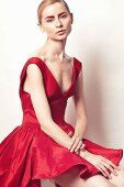 Junge Frau in rotem Petticoat-Kleid mit rot gefärbten Augenbrauen