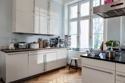 Einbauküche mit weissen Schrankoberflächen in Altbauwohnung mit Fischgrätparkett