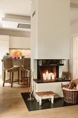 Wooden footstool beside candlelit fireplace in free-standing chimney breast and view of counter and bar stools in background