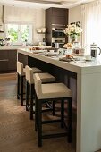 Elegant breakfast bar and upholstered bar stools in open-plan kitchen