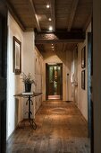 Long hallway with rustic wooden floor and modern spotlights on wood-beamed ceiling
