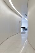 Glossy white marble floor and strip light in ceiling in curved hallway leading to grand piano in room at far end