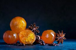 Kandierte Clementinen mit Sternanis und Zimtstangen auf blauem Schiefer
