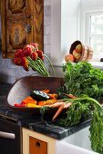 Fresh vegetables in a wooden bowl on a counter in a farmhouse kitchen