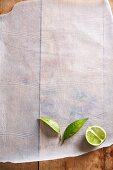 Half a lime with leaves on a piece of paper