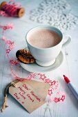 A cup of hot chocolate next to Christmas gift tags