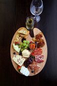 A supper platter with cheese, ham, crostini and grapes
