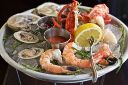 Oysters, prawns and crab with sauces and lemon on ice