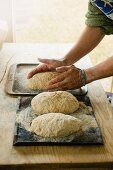 A person shaping loaves of bread by hand