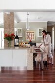 Floral armchairs at modern kitchen counter; woman arranging place settings