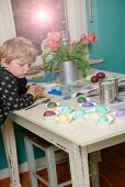 Child next to table looking at painted Easter eggs in paper cake cases