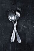 An old spoon and fork on a black surface