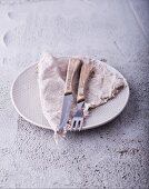 Rustic cutlery and a napkin on a plate
