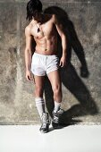 A young man wearing boxer shorts, knee socks and sliver trainers