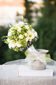 Festive bouquet of white flowers in concrete pot decorated with ribbon