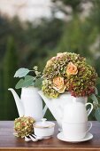 China tea and coffee pots and festive bouquet of apricot roses and hydrangeas