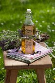 Bottle of oil decorated with posy of herbs on wooden stool