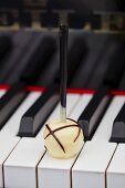 A white chocolate praline on the keys of a piano