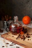 A bottle of spiced gin with star anise and nutmeg on a wooden board
