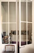 View through glass lattice doors into vintage bathroom with free-standing bathtub