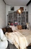 Extravagant round bed with fur blankets and retro standard lamp in front of white fitted shelves