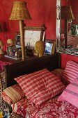 Striped cushions on daybed with leather-covered arm next to pictured and table lamp on table in vintage interior