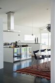 Ethnic rug in dining area in front of island counter in open-plan designer kitchen