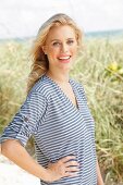 A young blonde woman on a beach wearing a striped t-shirt