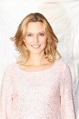 Blonde Frau in pastellrosa Pulli mit Lurex und Pailletten