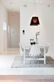 White classic chairs around white table below dark pendant lamps in contemporary interior