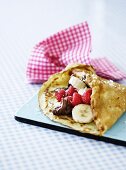 Crepe with raspberries, bananas, chocolate and coconut