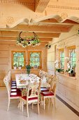 Painted, carved wooden chairs around dining table in corner of room in wooden house