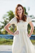 A young woman on a beach wearing a white summer dress