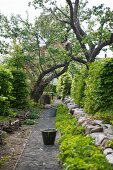 Gartenweg flankiert von Obstbäumen und niedriger Natursteinmauer