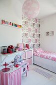 Girl's bedroom with pink accents, child's bed and section of wall with house-patterned wallpaper