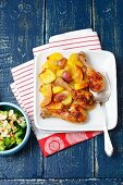Baked chicken drumsticks with lemons and potatoes served with steamed broccoli and flaked almonds