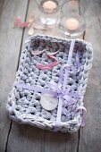 Crocheted basket made from lilac Zpagetti yarn decorated with ribbon and gift tag as a gift