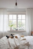Naturweiße Tagesdecke auf Bett vor Sprossenfenster in ländlichem Schlafzimmer