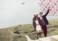 A young couple with a kite walking trough a dune landscape