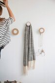 Woman hanging hat on coat pegs made from round wooden discs