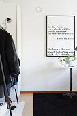 Scented pelargonium on bistro table below black-framed poster of black text on white background