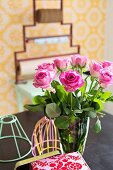 Glass vase of pink roses and pastel lampshade frames
