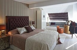 Double bed with button-tufted headboard against striped wallpaper in elegant bedroom