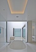 Designer-Badewanne unter indirekt beleuchtetem Deckenfeld, in modernem Atriumhaus