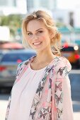 A young blonde woman wearing a light pink shirt with a silk scarf