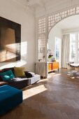 Modern sofa in living area in front of archway with lead-glazed surround and view into dining room