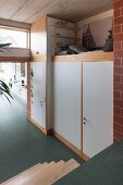 Fitted cupboards and loft bed in industrial loft apartment